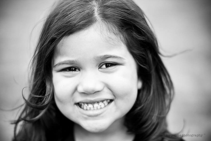a star is born... A black and white close-up of a young girl with long hair smiling directly at the camera. Her expression is joyful, and the background is blurred, emphasizing her face.