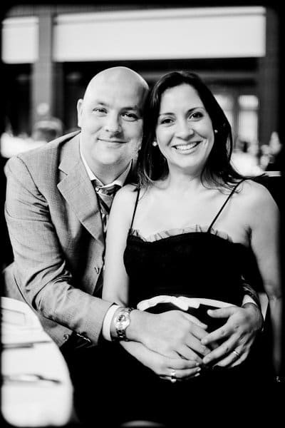 justin and meredith get hitched A smiling couple poses together in a black and white photo. The man is seated, wearing a suit, while the woman in a dress stands beside him with his arm around her. They appear at a formal event, with softly out-of-focus background details.
