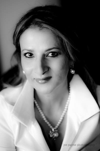 Black and white portrait of a woman with long hair, wearing a white collared shirt, pearl necklace, and earrings, smiling softly at the camera—an elegant example of composition basics as discussed in tutorial two.