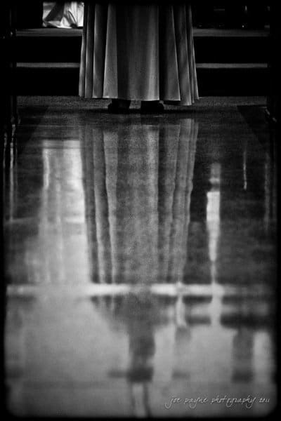 raleigh wedding photographer - jenna and ryan Black and white photo showing the lower half of a person in a long garment, standing on a reflective floor. Their reflection is visible, creating a mirrored effect.