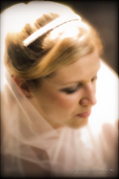 raleigh wedding photographer - jenna and ryan Bride wearing a veil, looking down with a soft focus effect. Her hair is styled elegantly, and a hairband is visible. The image has a warm, dreamy ambiance.