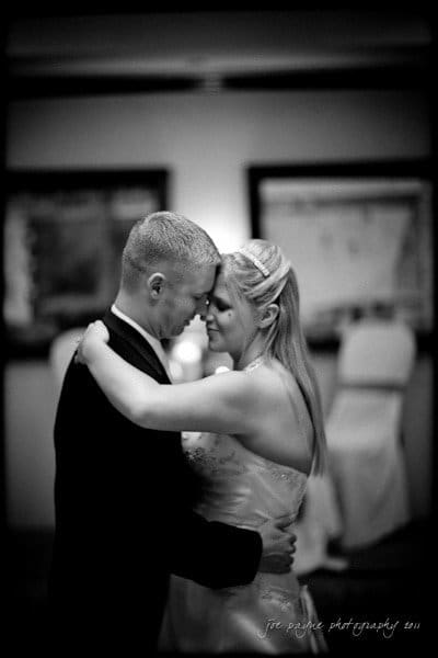 raleigh wedding photographer - jenna and ryan A black and white image of a couple dancing closely. They have their foreheads touching, eyes closed, and content expressions. The background is softly blurred, highlighting their intimate moment.