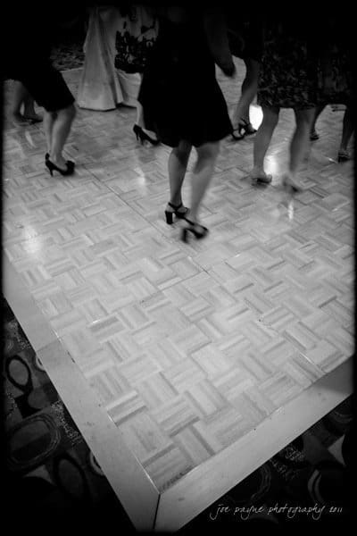 raleigh wedding photographer - jenna and ryan Black and white image of people dancing on a wooden floor. Only their legs and shoes are visible. The scene captures movement and elegant footwear, including heels.
