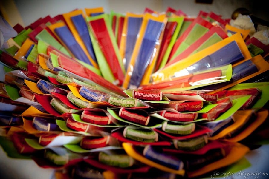 A vivid collection of colorful envelopes or packets fan out in a circular pattern, showcasing hues of red, blue, green, orange, and yellow. They create a visually striking and artistic display.