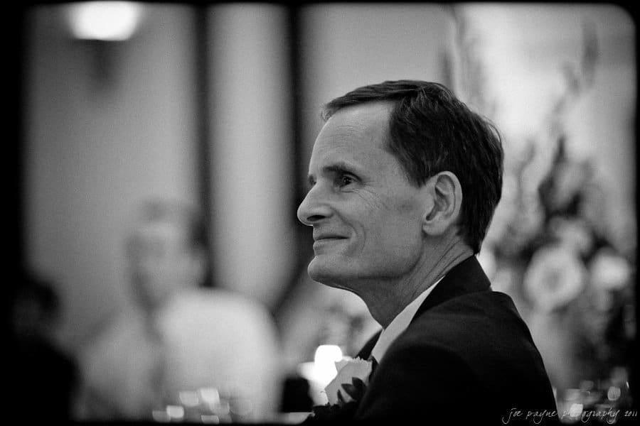 carolina inn weddings | allison and matthew Black and white image of a person in profile, dressed formally, with a gentle smile. The background is softly blurred with elegant decor, creating a serene atmosphere.