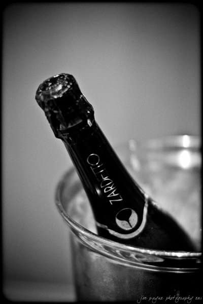 Black and white image of a bottle of Zarotto champagne resting in an ice bucket, with condensation visible on the bottle. The background is softly blurred.