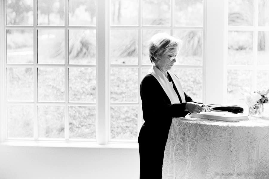 A person stands at a round table in front of large windows, engrossed in reading or writing, with soft, natural light flooding the room, creating a calm and peaceful ambiance.