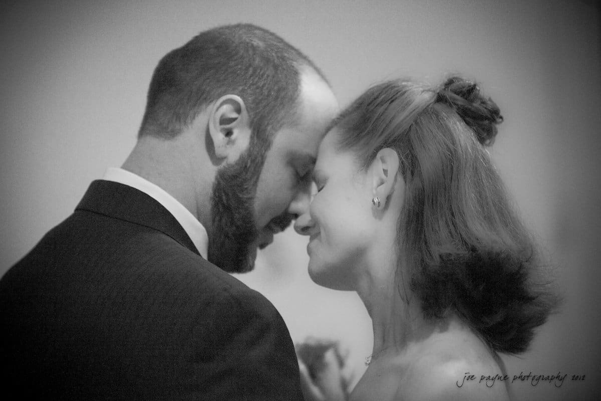 lake lure north carolina wedding photography ~ shannon and paul A black and white photo of a couple sharing an intimate moment. They are standing close with their foreheads touching, eyes closed, and smiling softly. The background is softly blurred.