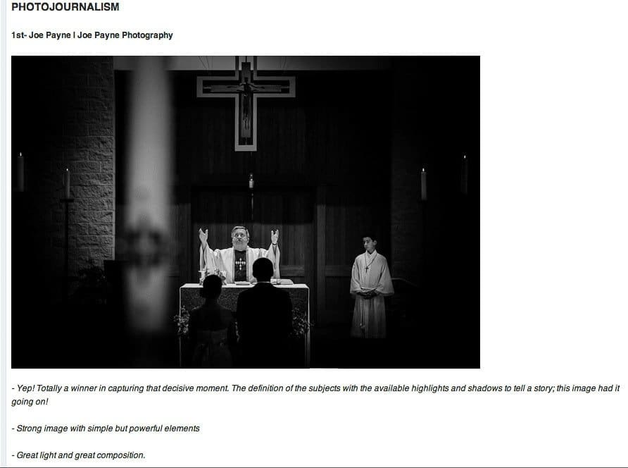 A priest stands at an altar with arms raised, flanked by two altar servers in a dimly lit church. A large cross is visible above them. The image is in black and white, highlighting the contrast and composition.