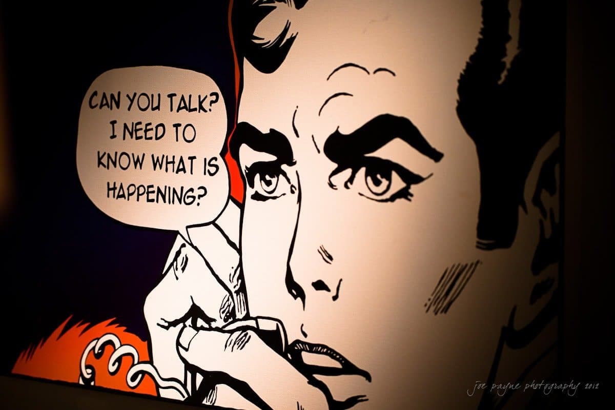 Comic-style illustration of a worried person holding a phone to their ear. A speech bubble reads, Can you talk? I need to know what is happening? The image uses bold lines and contrast for dramatic effect.