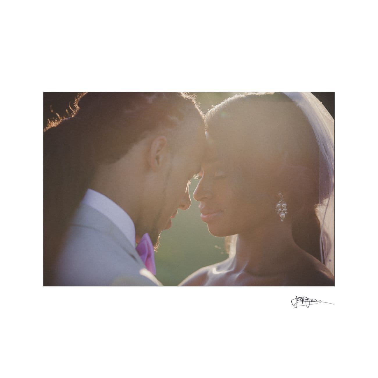 A romantic close-up of a couple on their wedding day, gently touching foreheads with closed eyes. The groom wears a suit, and the bride is in a veil and earrings. Soft, warm lighting adds a dreamy effect.