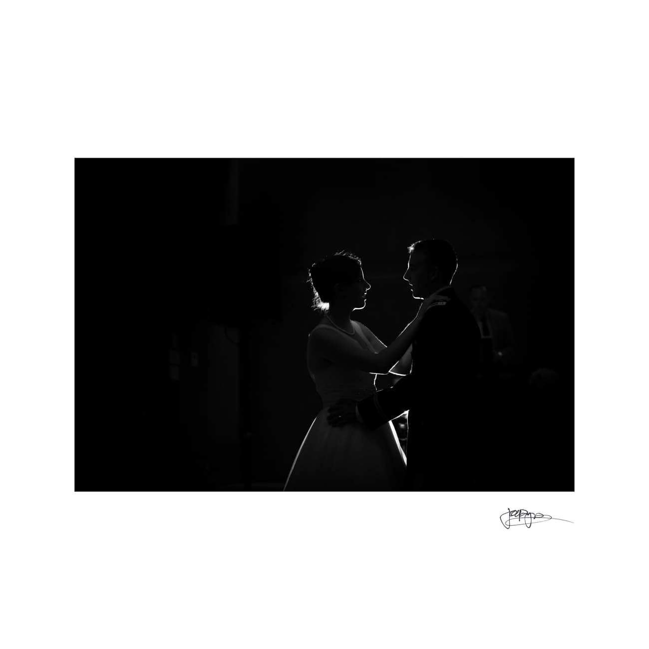 chapel hill wedding photographer - alexandra & john A silhouetted couple sharing a dance in a dimly lit room. The lighting highlights their profiles as they hold each other closely, creating a romantic and intimate atmosphere.