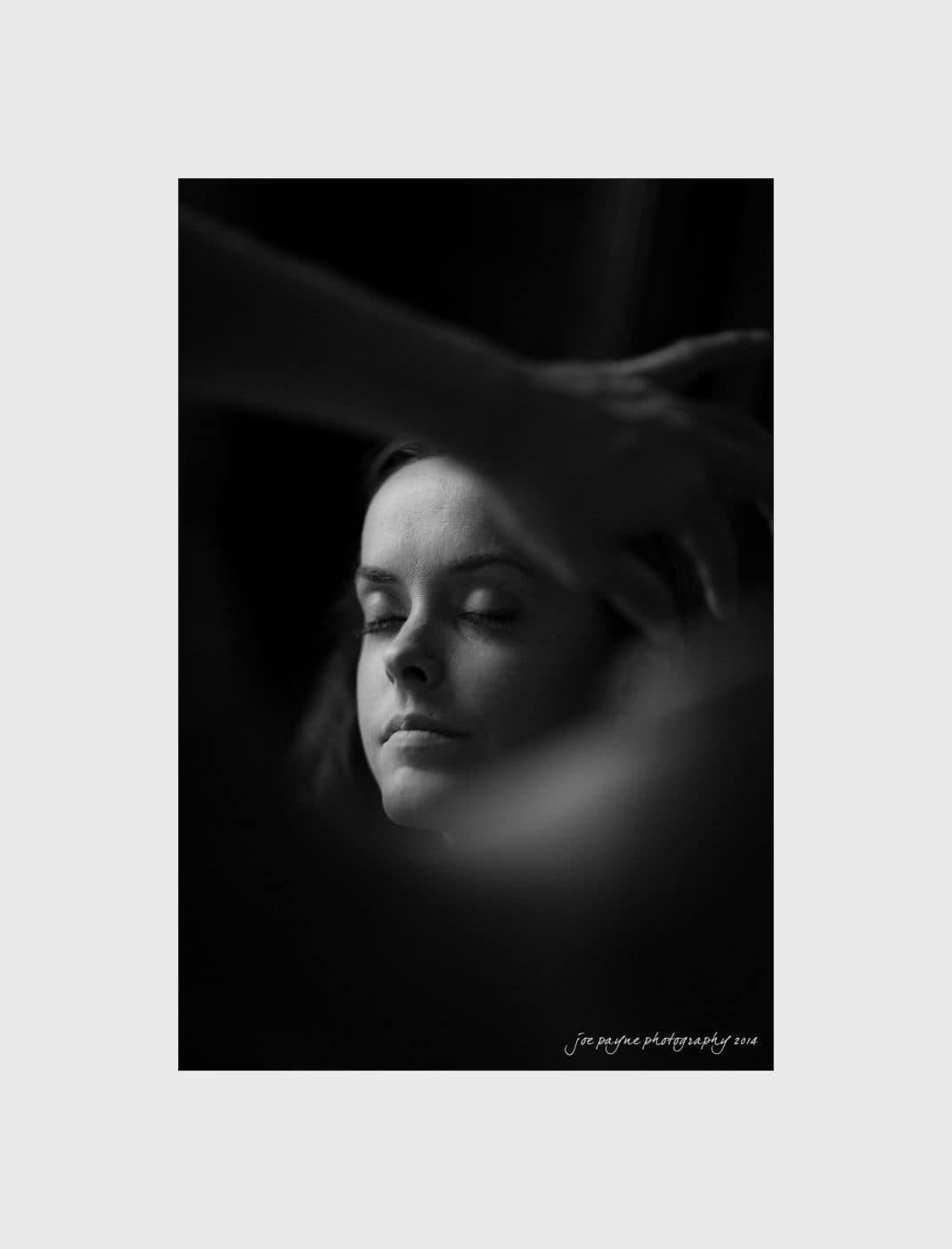 wilmington wedding photographer - nichole & eric Black and white photo of a woman with closed eyes, relaxed as a hand gestures near her head. Soft lighting accentuates the serene atmosphere.