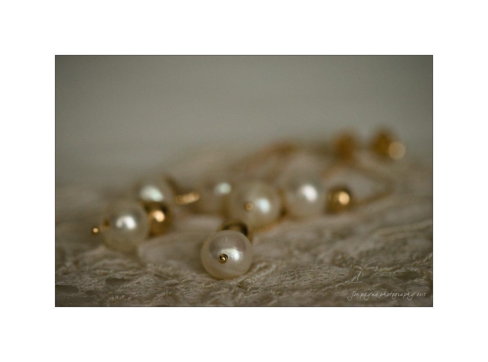 Close-up of a pearl necklace with gold accents resting on a textured fabric surface. The pearls are round and glossy, reflecting light softly, creating an elegant and classic appearance.