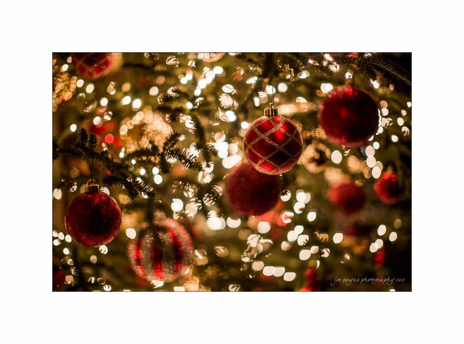 A close-up of a Christmas tree adorned with red ornaments and twinkling white lights, creating a warm and festive atmosphere.