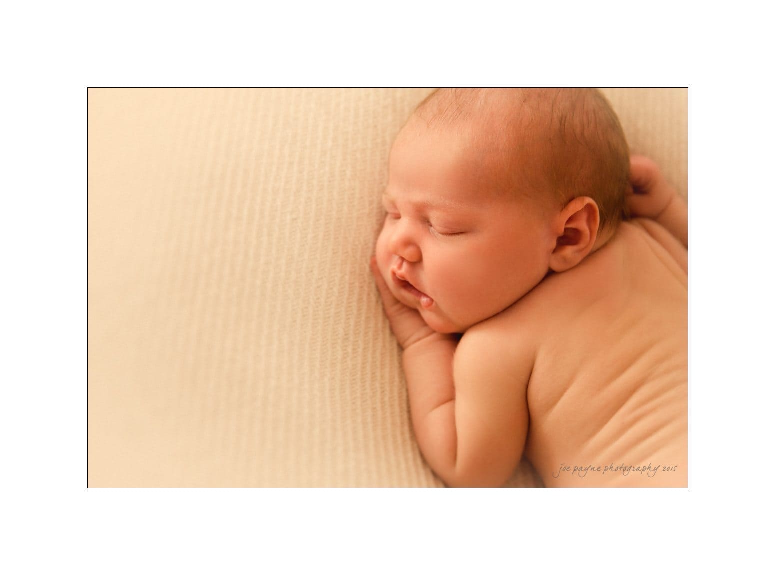 raleigh newborn photographer - baby patton A close-up image of a peacefully sleeping baby lying on a soft, light-colored surface. The baby is resting on one side, with a serene expression and minimal clothing.