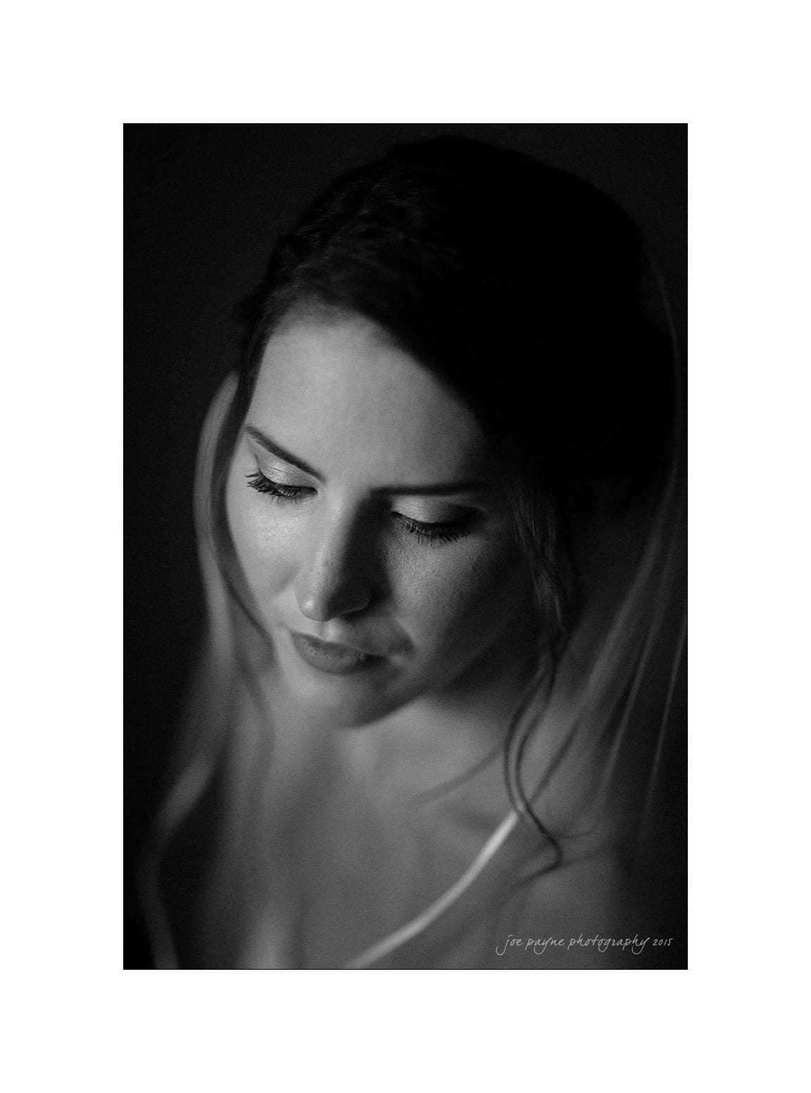 NC wedding photography - rachel & joe Black and white portrait of a woman with closed eyes, softly lit from the side. She appears serene and thoughtful, with a delicate veil over her hair, and the background is dark, enhancing the intimate mood.