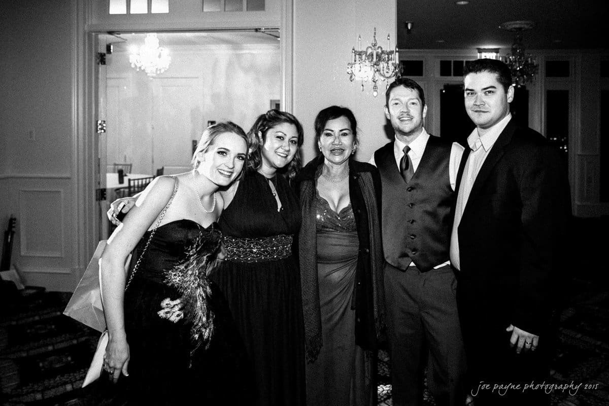 charlotte wedding photographers - ashley & matt A black and white photo of six people dressed formally, smiling at the camera while standing in an elegant interior with chandeliers. The three women wear gowns, and the three men wear suits and ties.