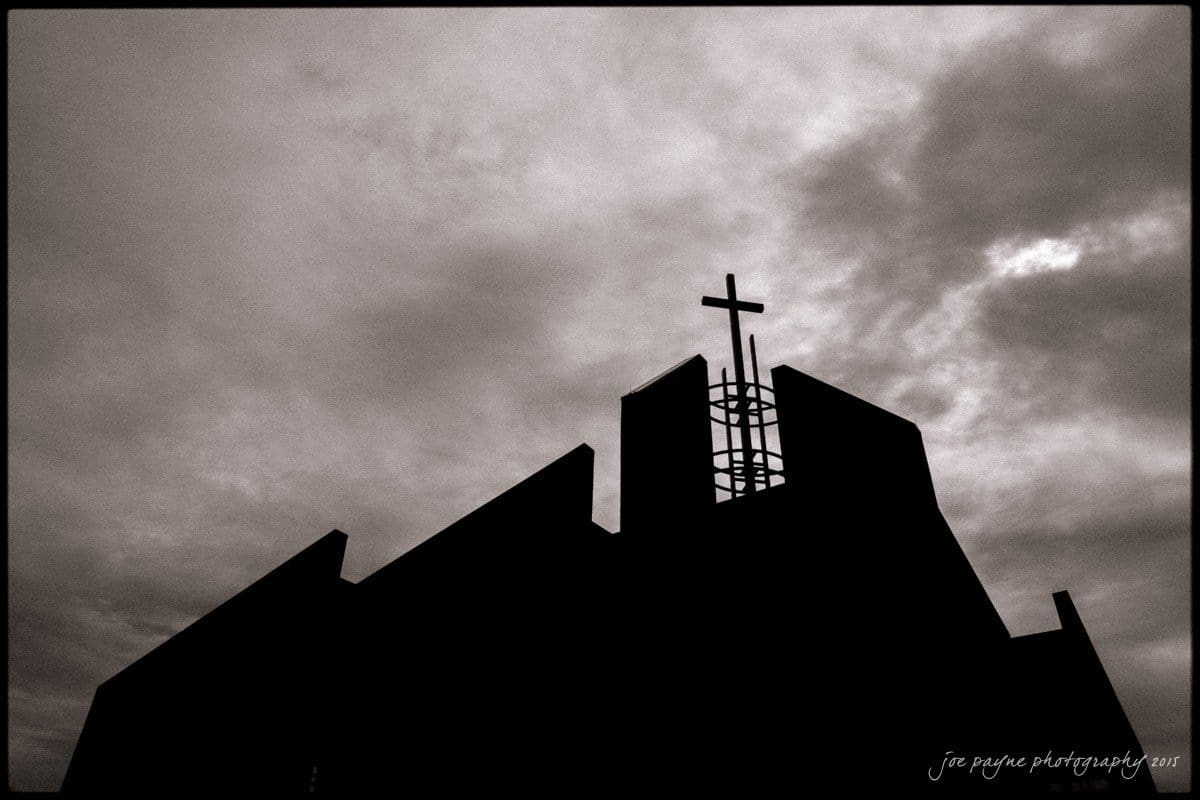 charlotte wedding photographers - ashley & matt Silhouetted church with a cross against a dramatic, cloudy sky.