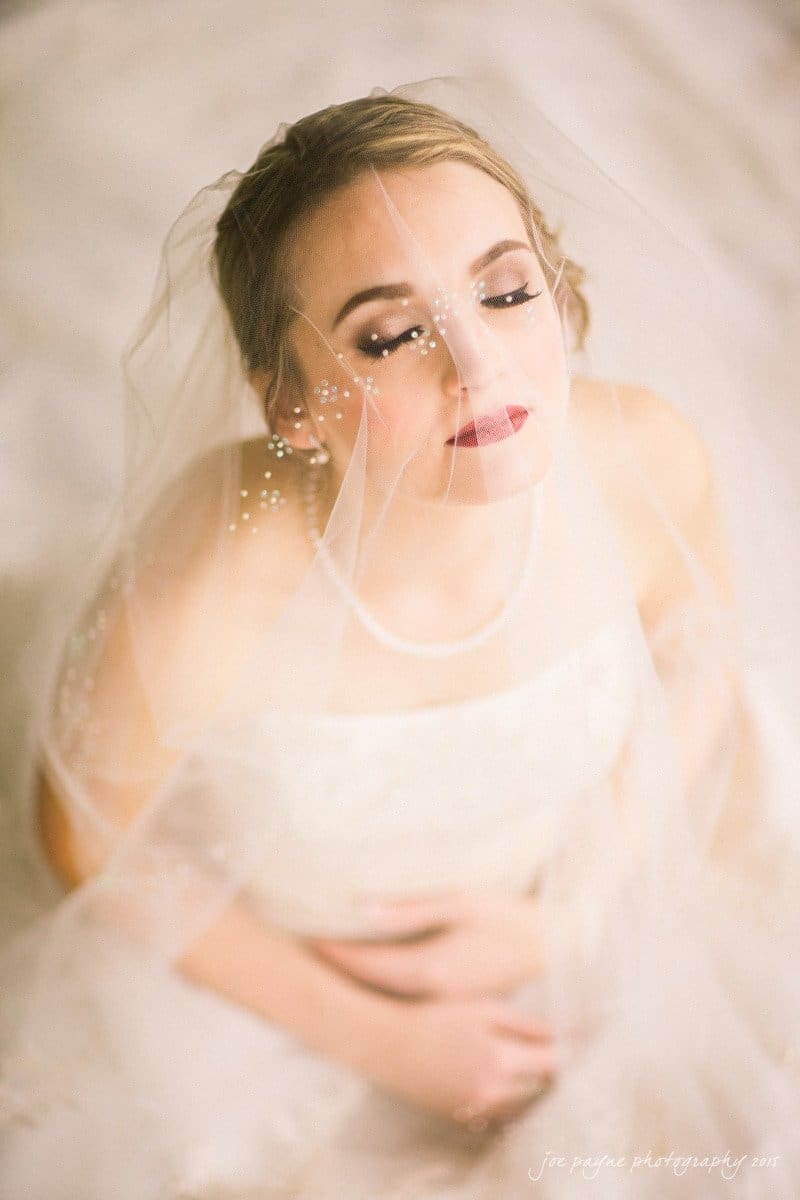 charlotte wedding photographers - ashley & matt A bride with closed eyes softly smiles while wearing a veil and an off-the-shoulder gown. The photo has a dreamy, soft-focus effect.