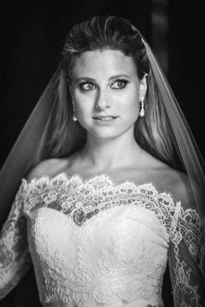An elegant fine art bridal portrait of Sara standing before the grand stone entryway of Duke University Chapel during her bridal portrait session.