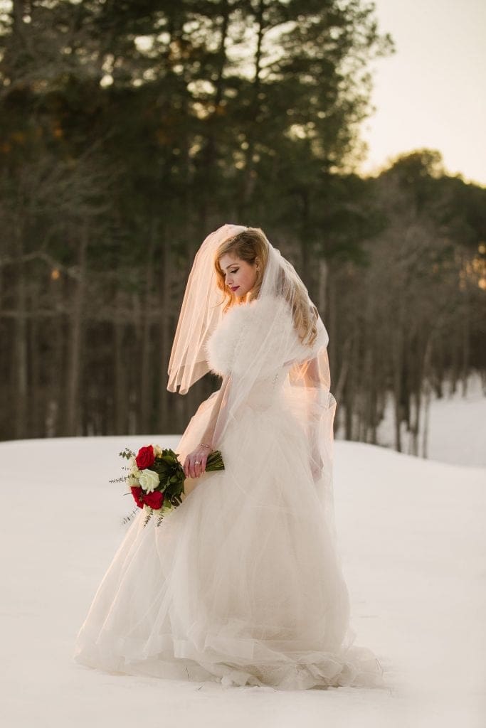 A beautiful winter bridal portrait in the fresh snow at the Washington Duke Inn, with the last rays of sunset giving her bridal veil a subtle, warm golden glow.