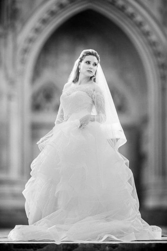 A timeless black and white bridal portrait of a bride posing elegantly inside the stone architecture of Duke University Chapel.