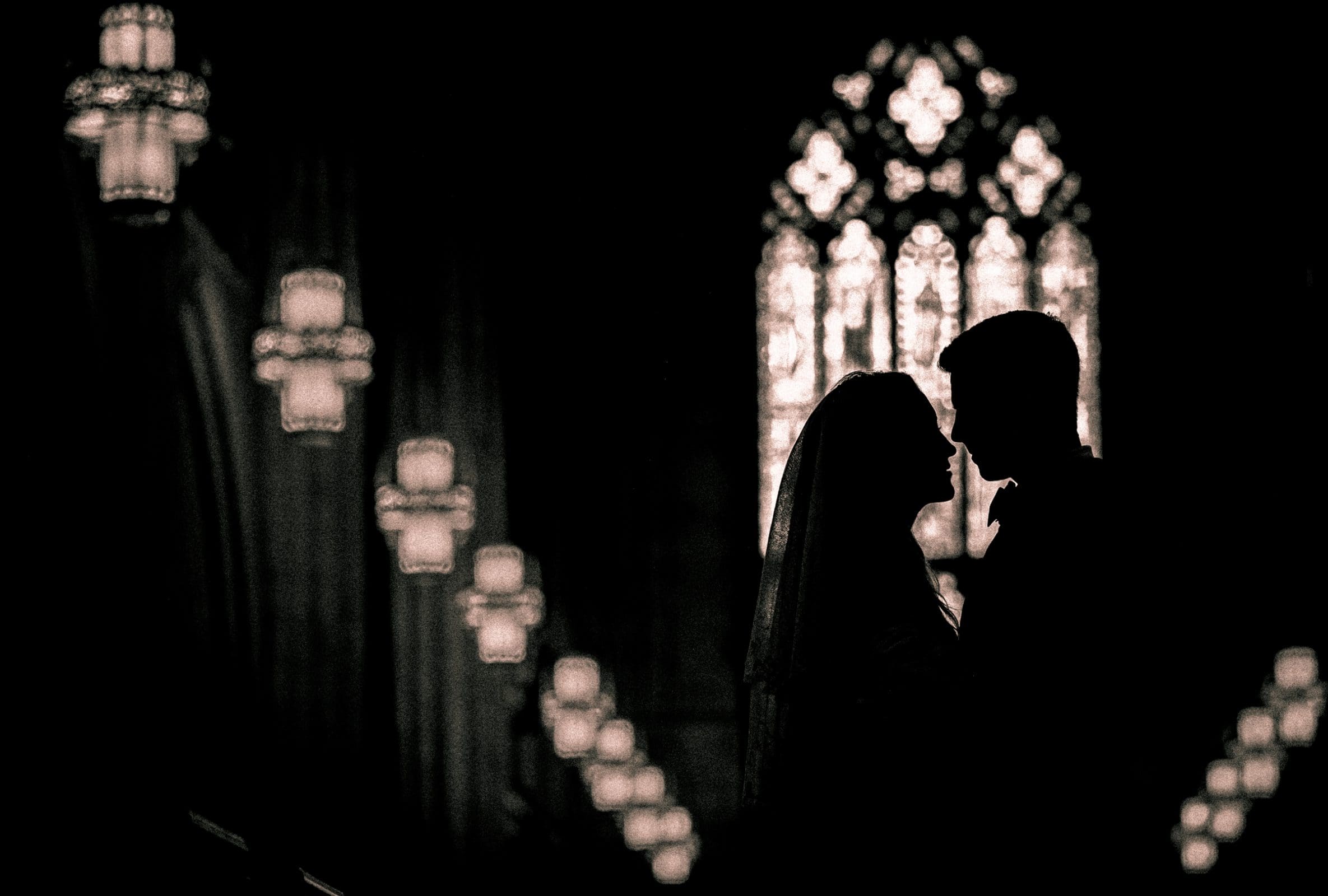 Dramatic architectural silhouette of a bride and groom framed in a grand gothic window at Duke Chapel by Durham wedding photographer Joe Payne.