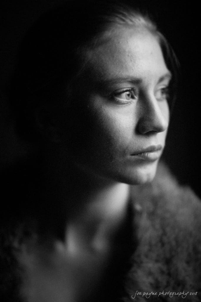 parker j pfister's french revolution workshop review Black and white portrait of a person gazing contemplatively to the side, illuminated by soft light. The contrast highlights their facial features and expression. Joe Payne Photography 2011 is noted at the bottom.