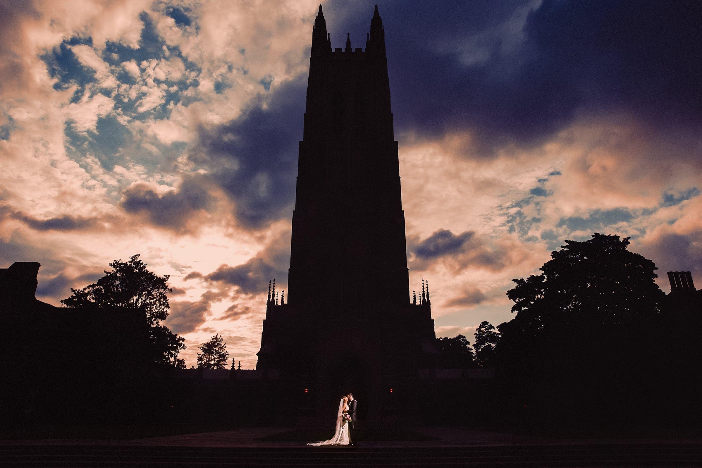 Dramatic outdoor silhouette portrait of a couple in front of the towering Duke Chapel by Durham wedding photographer Joe Payne.