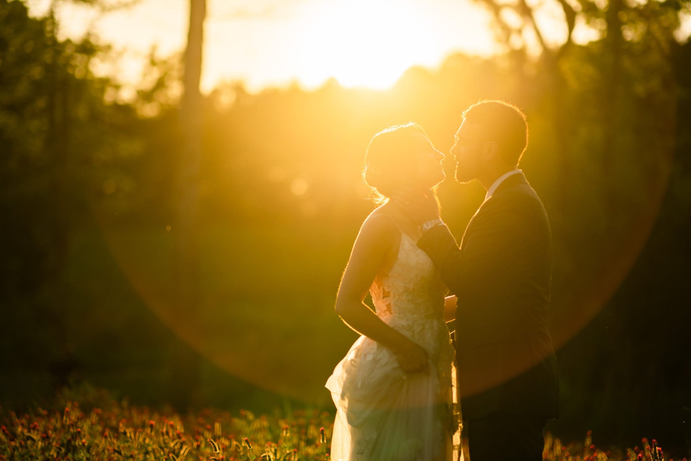 union grove farm wedding photography - kaylyn & jeremy A couple stands in a field during sunset, embraced and gazing at each other. The soft golden light creates a romantic and serene atmosphere, casting silhouettes against the warm glow of the sun—a perfect moment captured by Union Grove Farm wedding photography.