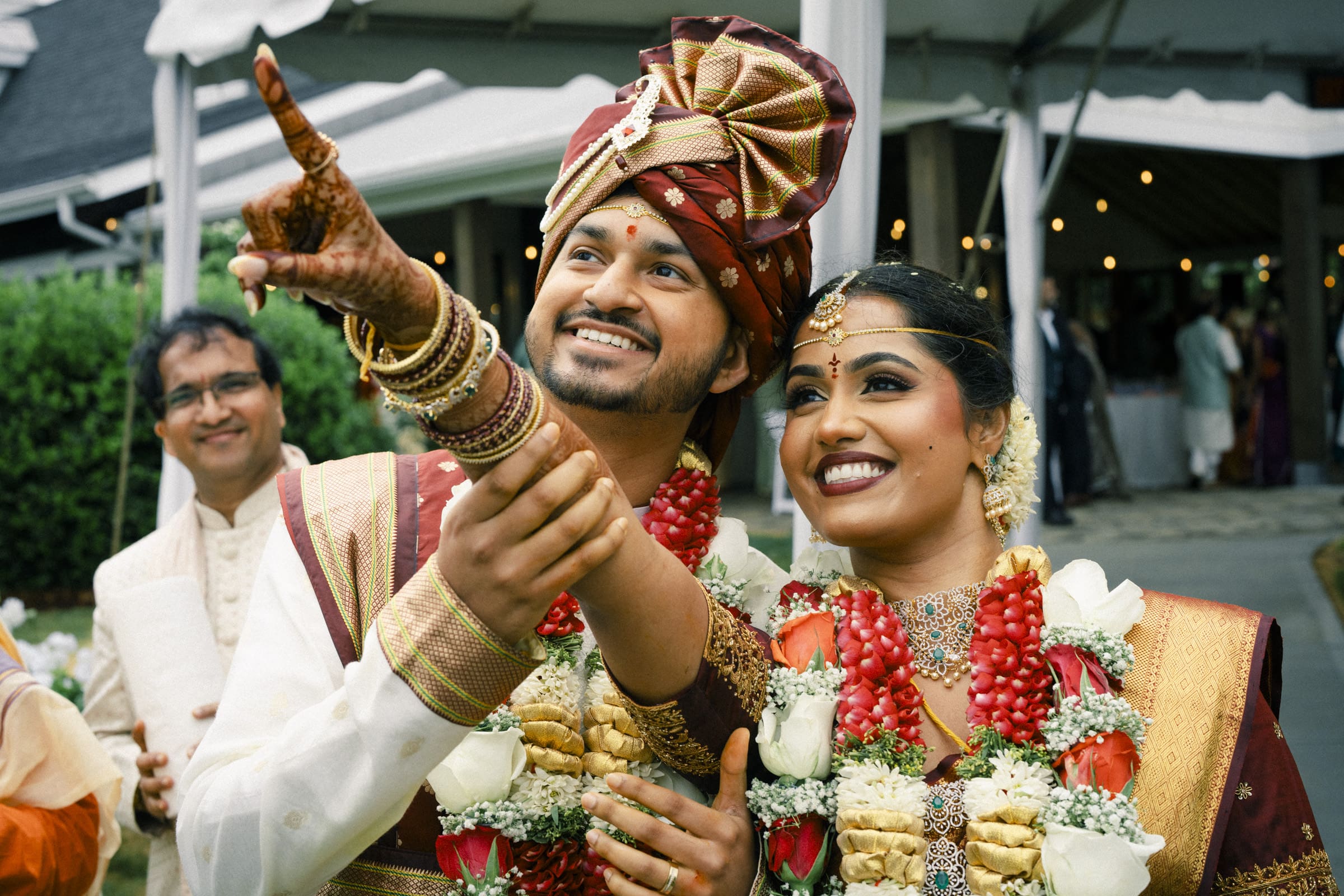 A bride and groom smile joyfully as they look up to point at the sacred star during their wedding rituals at The Pavilion at Carriage Farm.