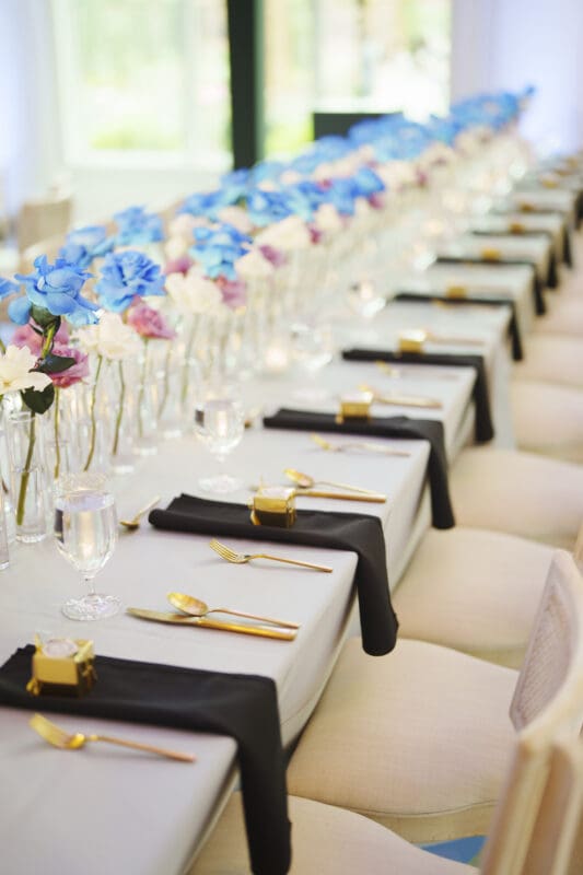 Elegant indoor reception tablescapes decorated with black linens, gold accents, and lush floral arrangements for a Donovan Manor wedding.