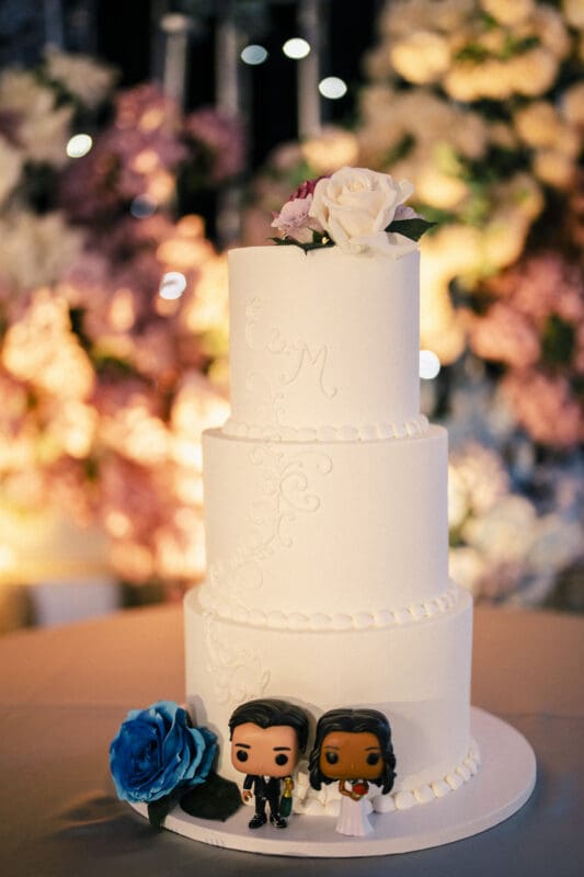 A beautiful three-tier white floral wedding cake displayed at a luxury Indian wedding reception at Donovan Manor.