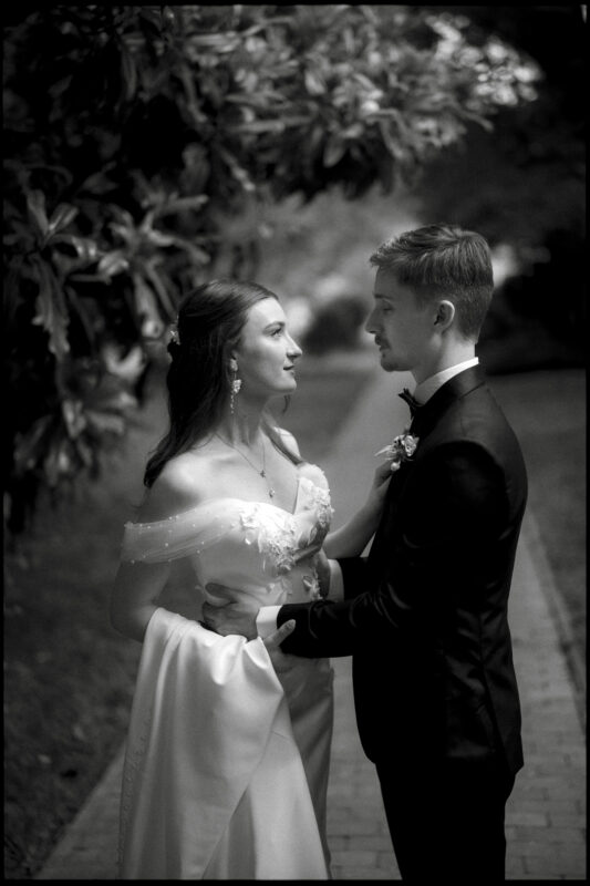 A bride and groom stand facing each other on a garden path at the Carolina Inn in Chapel Hill, holding each other and gazing into each other’s eyes. The image, captured in black and white, perfectly evokes the timeless romance of their elegant spring celebration. By award-winning Raleigh wedding photographer, Joe Payne.