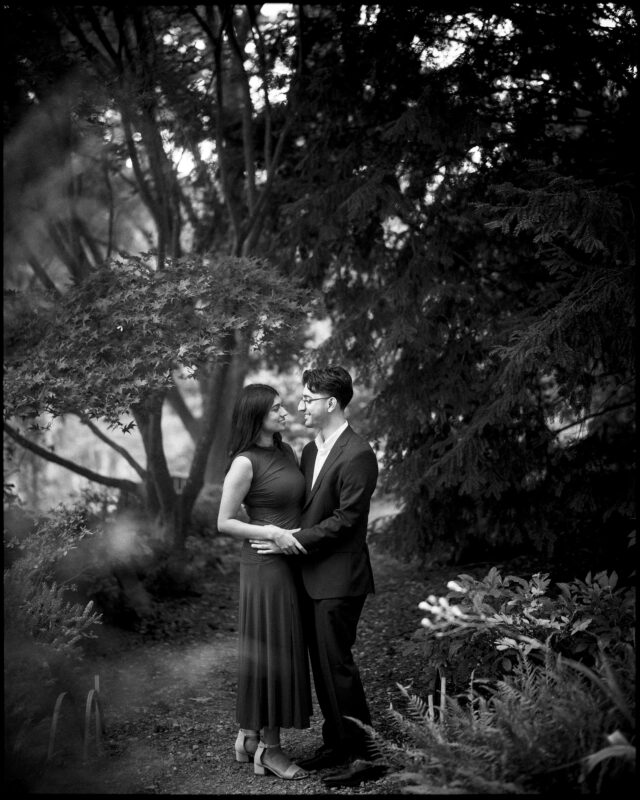 A couple stands facing each other in Duke Gardens, holding hands for their engagement photography. By award-winning Raleigh wedding photographer, Joe Payne.