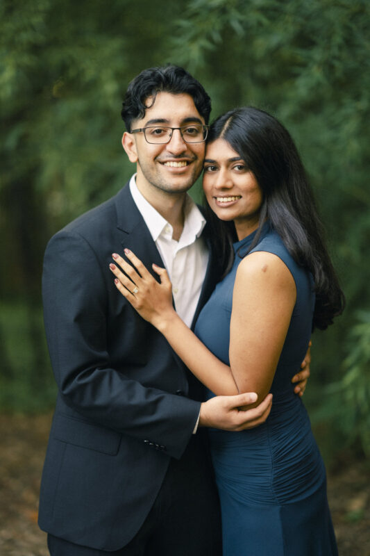 A man in a suit and a woman in a blue dress posing together for engagement photography at Duke Gardens. By award-winning Raleigh wedding photographer, Joe Payne.